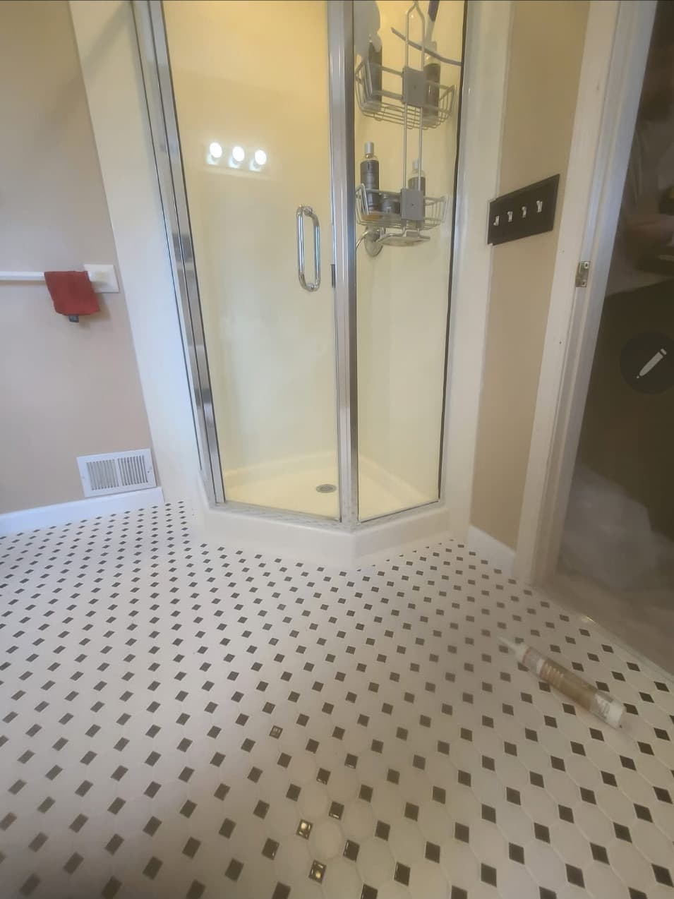 Corner glass shower enclosure with black and white mosaic tile floor in a Minneapolis bathroom